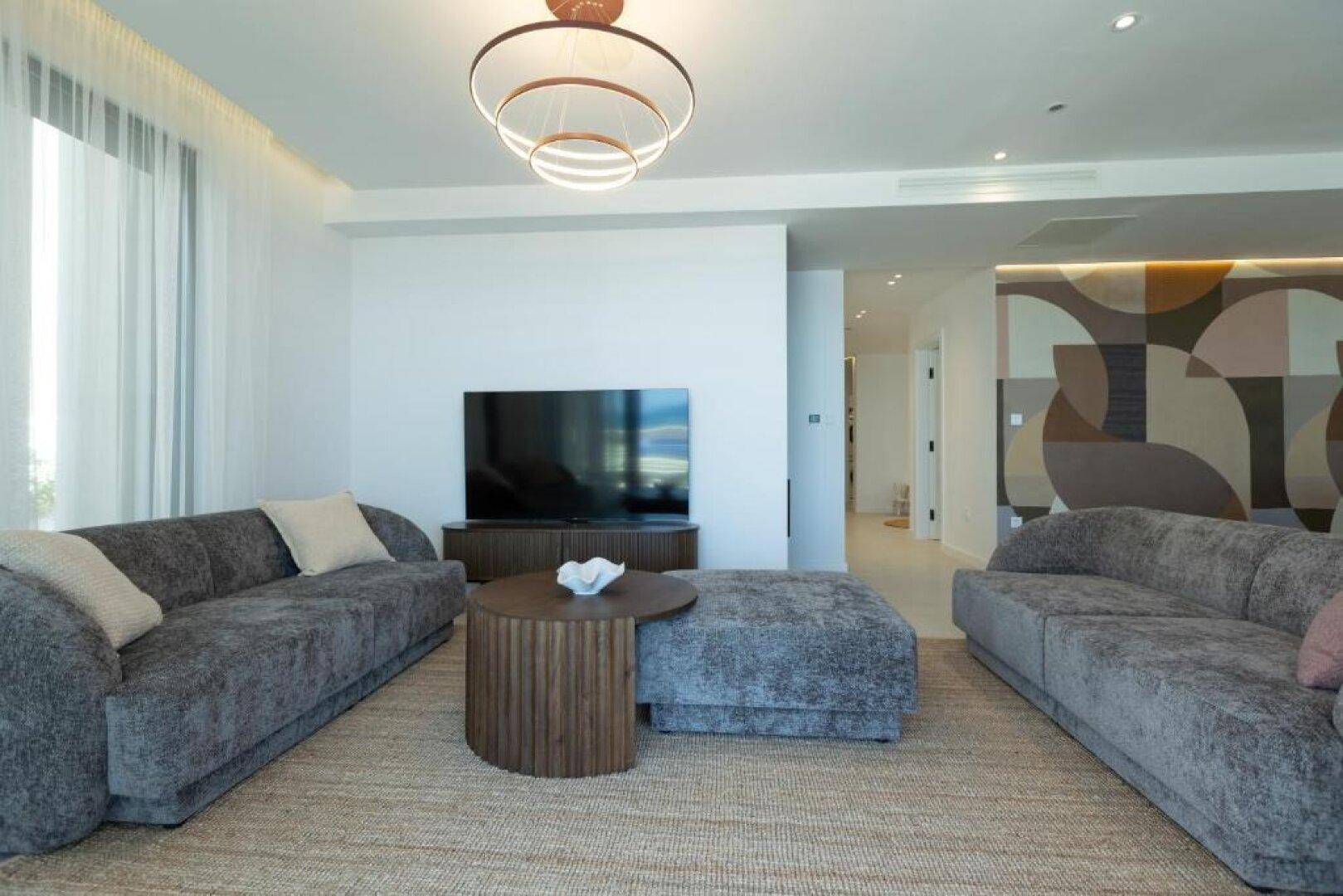 Geräumiges Wohnzimmer mit bequemen Sofas, modernem Dekor und viel Tageslicht.