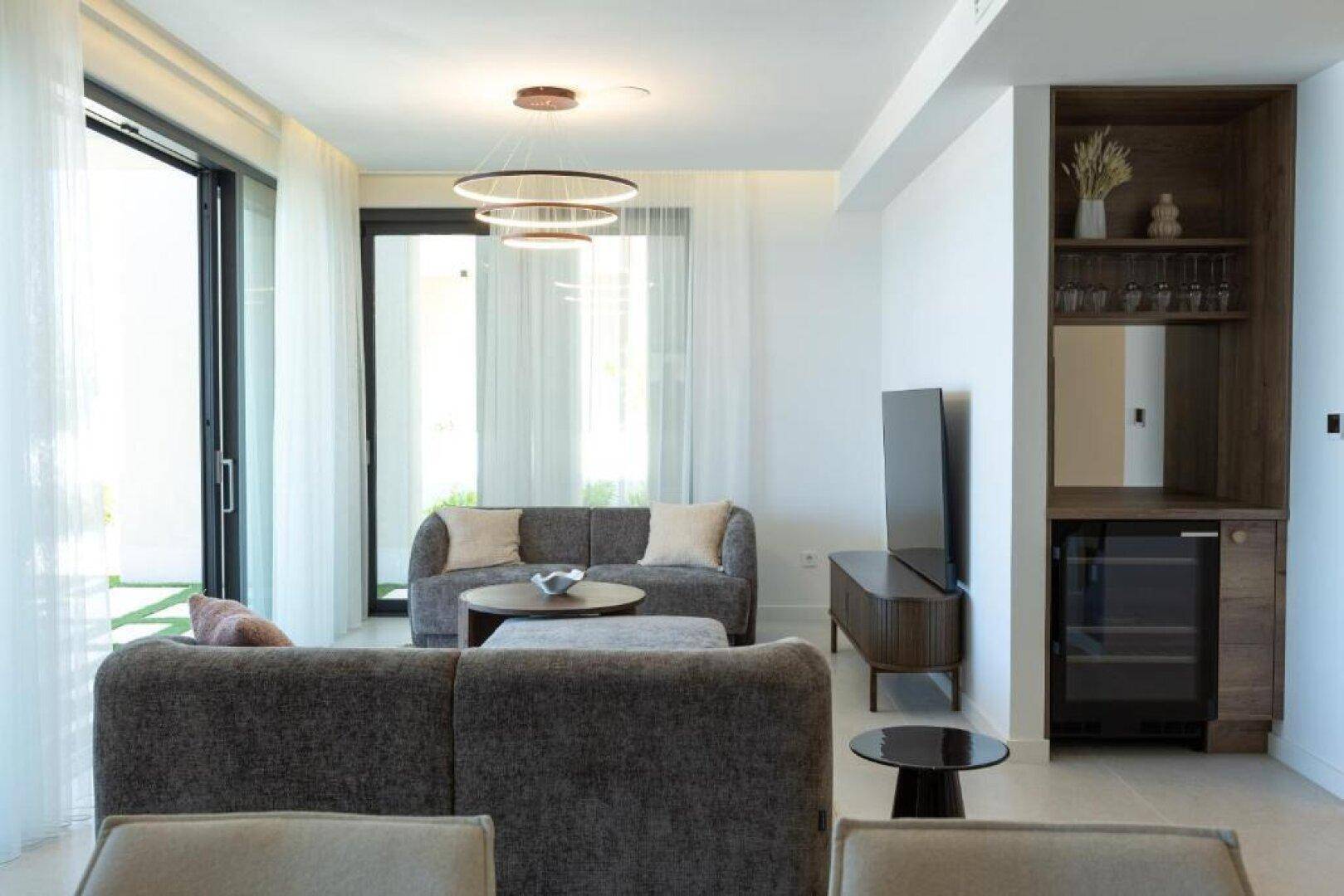 Helles Wohnzimmer mit bequemen Sofas, integriertem Weinkühler und Zugang zur Terrasse.