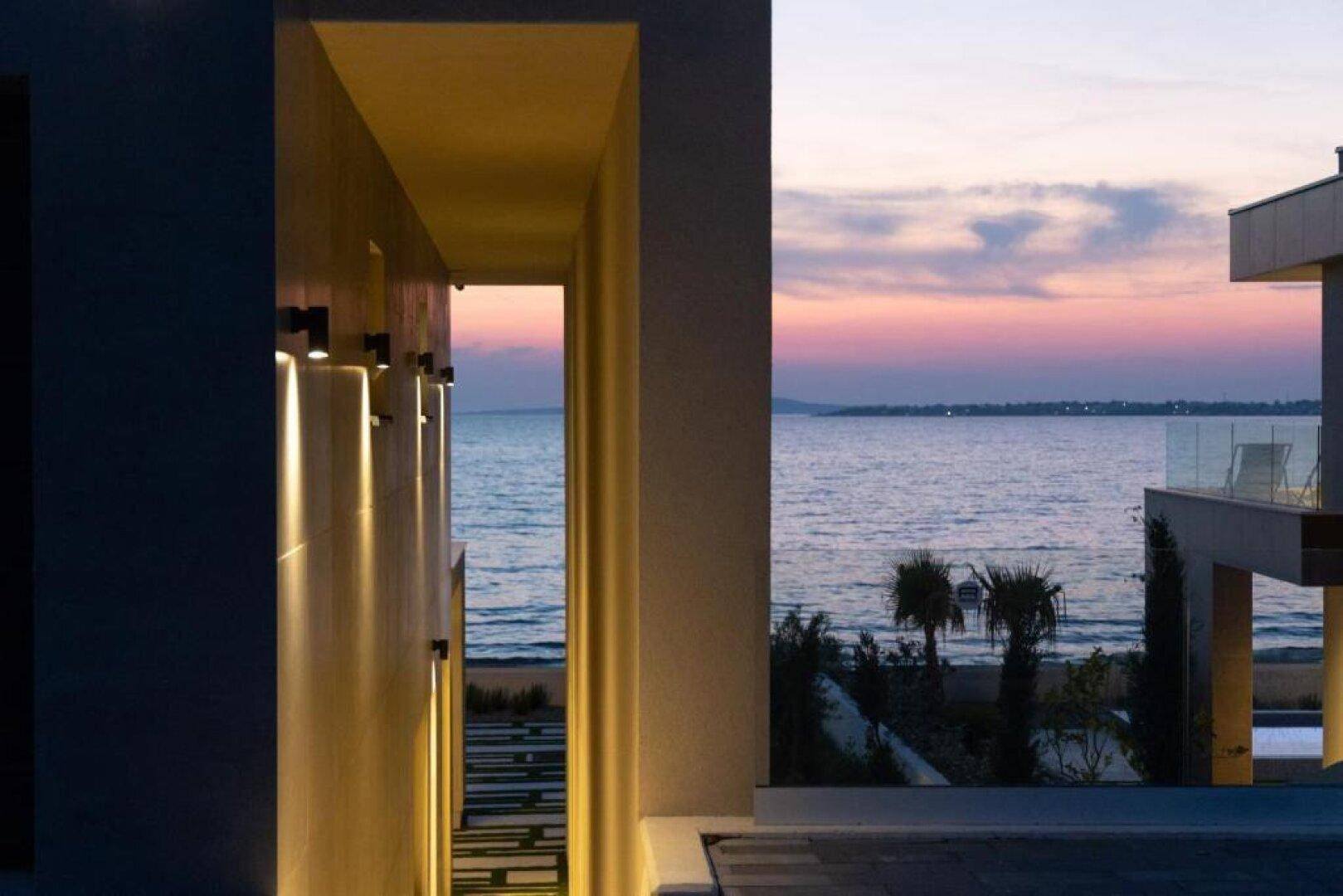 Architektonischer Durchgang mit Beleuchtung und Blick auf das Meer bei Sonnenuntergang.