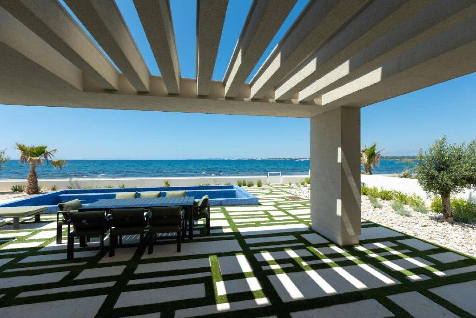 Überdachte Terrasse mit modernem Essbereich und weitem Blick auf das Meer.