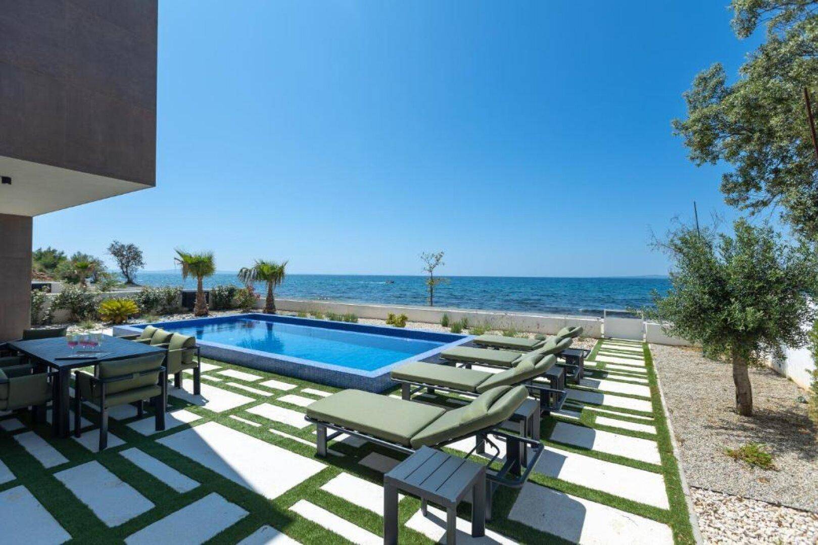 Geräumiger Außenbereich mit Esstisch, Pool und Liegestühlen, bietet einen herrlichen Meerblick.
