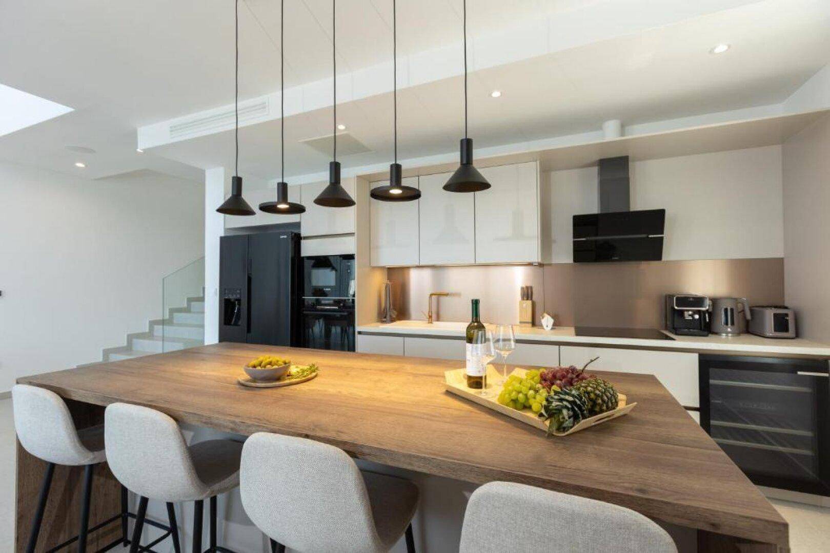 Helle, moderne Küche mit großer Kücheninsel und hochwertigen Einbaugeräten für kulinarische Erlebnisse.