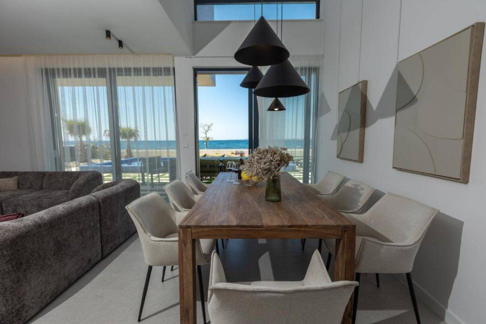 Eleganter Essbereich mit Holztisch und modernen Stühlen, bietet einen weiten Blick auf das Meer.