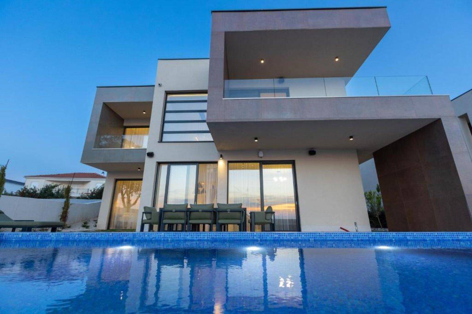 Moderne Villa mit beleuchtetem Pool und Terrasse, die zum Entspannen im Freien einlädt.