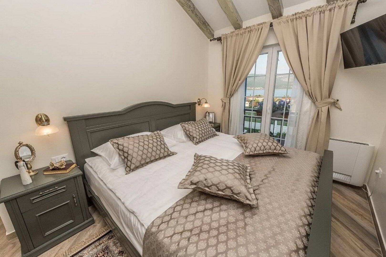 Helles Schlafzimmer mit Doppelbett, traditionellen Möbeln und einem Fenster mit Meerblick.
