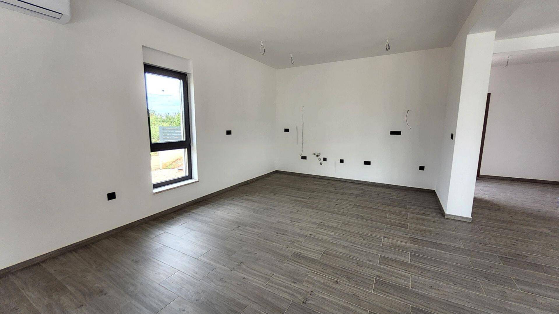Heller, unmöblierter Raum mit modernen Fliesen, einem Fenster und Klimaanlage.