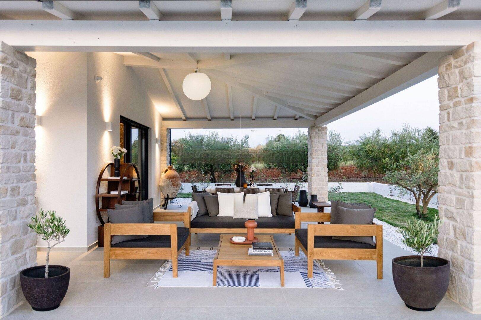 Gemütliche überdachte Terrasse mit bequemen Lounge-Möbeln und Blick ins Grüne.