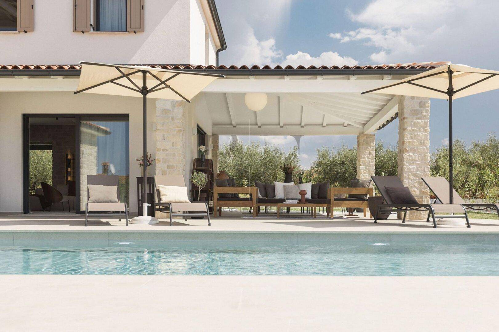 Erfrischender Poolbereich mit Sonnenliegen und angrenzender überdachter Terrasse.
