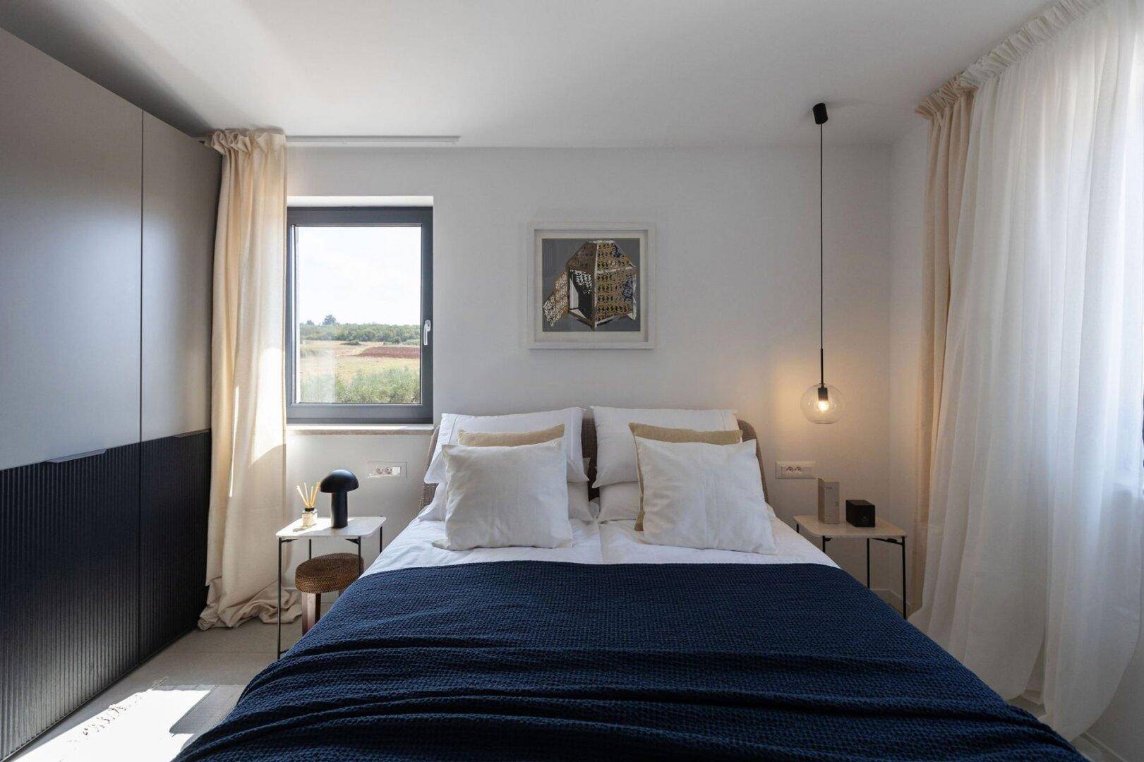Ruhiges Schlafzimmer mit großem Fenster, bequemen Bett und integriertem Kleiderschrank.