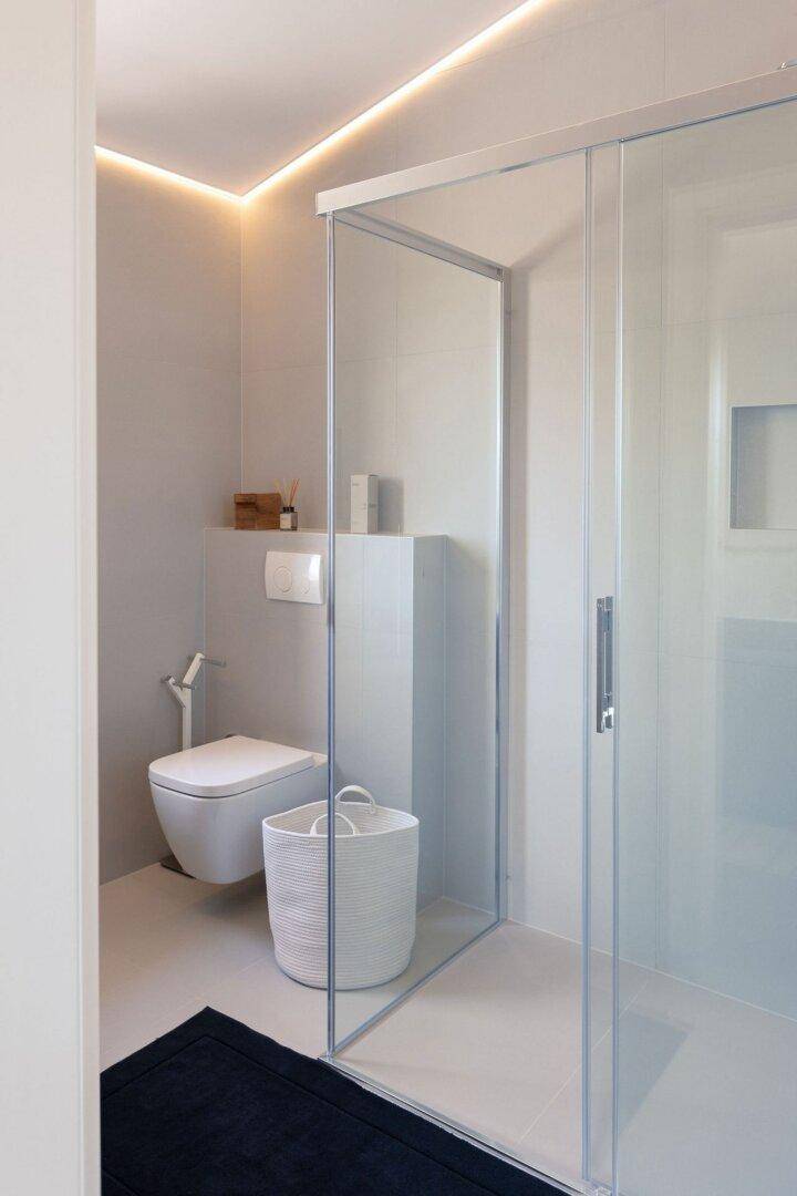 Helles Badezimmer mit wandhängendem WC und geräumiger Duschkabine aus Glas.