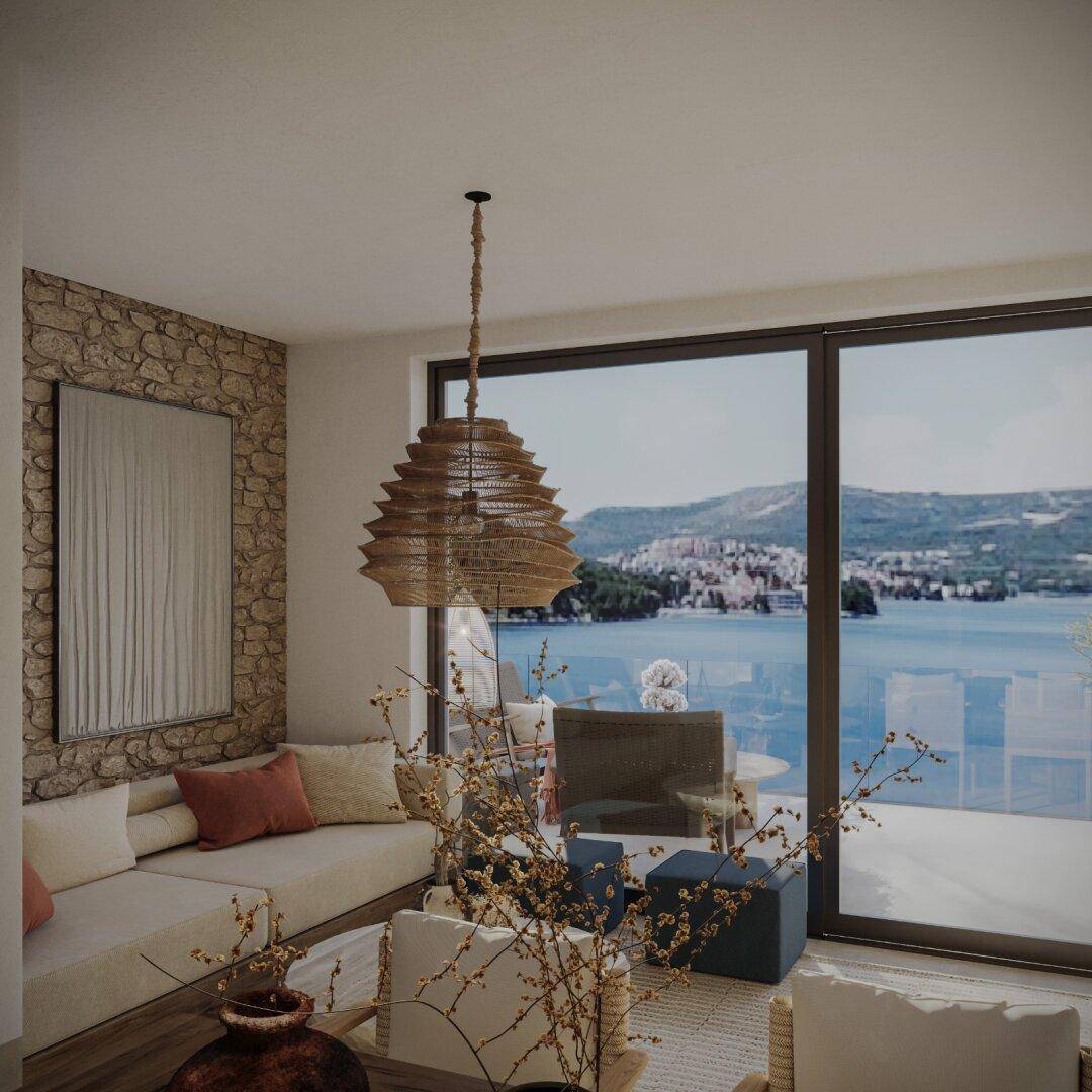 Helles Wohnzimmer mit Steinwand, großen Fenstern und weitem Meerblick.