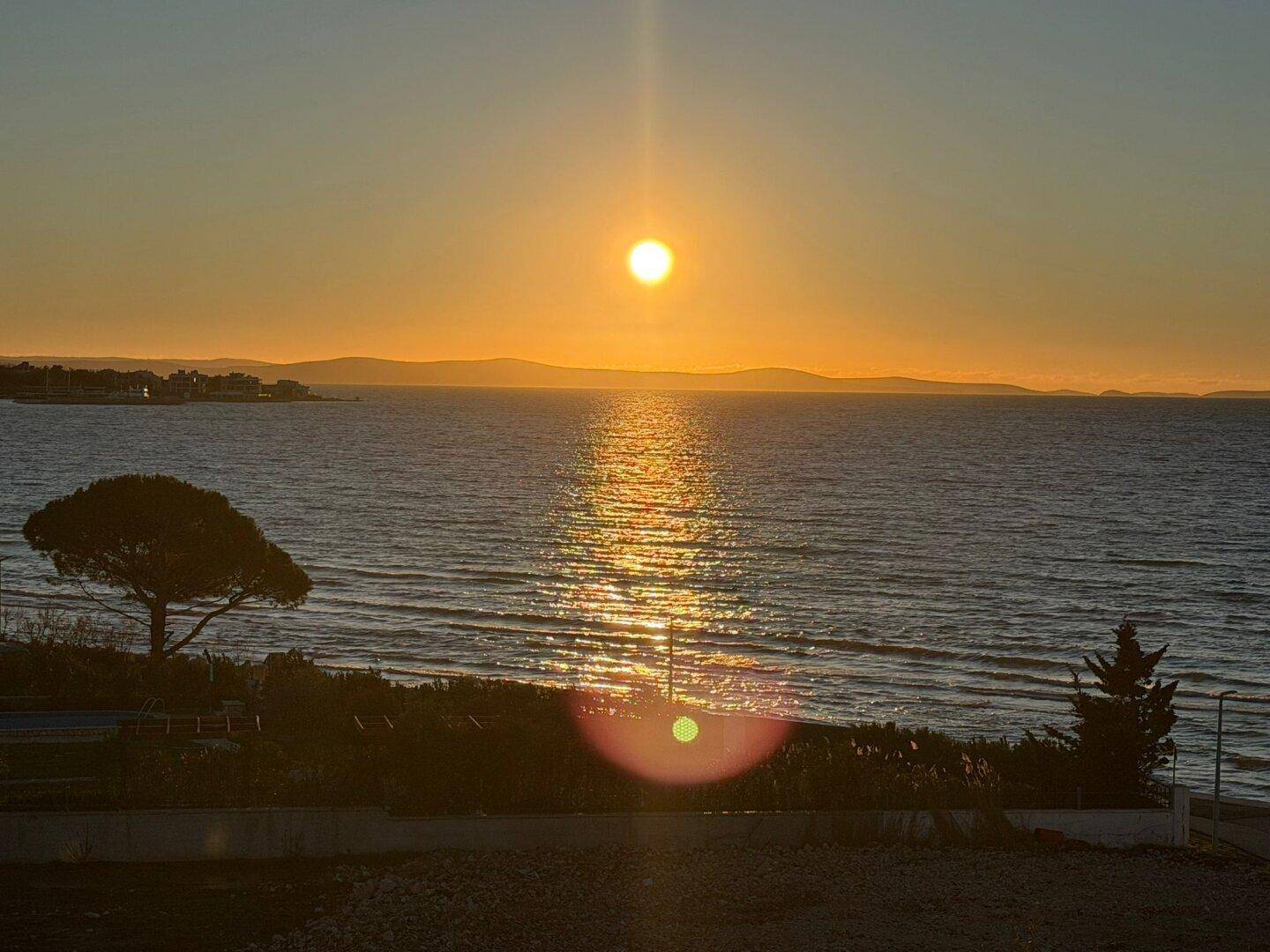 Atemberaubender Sonnenuntergang über dem Meer mit glitzerndem Wasser und Horizont.