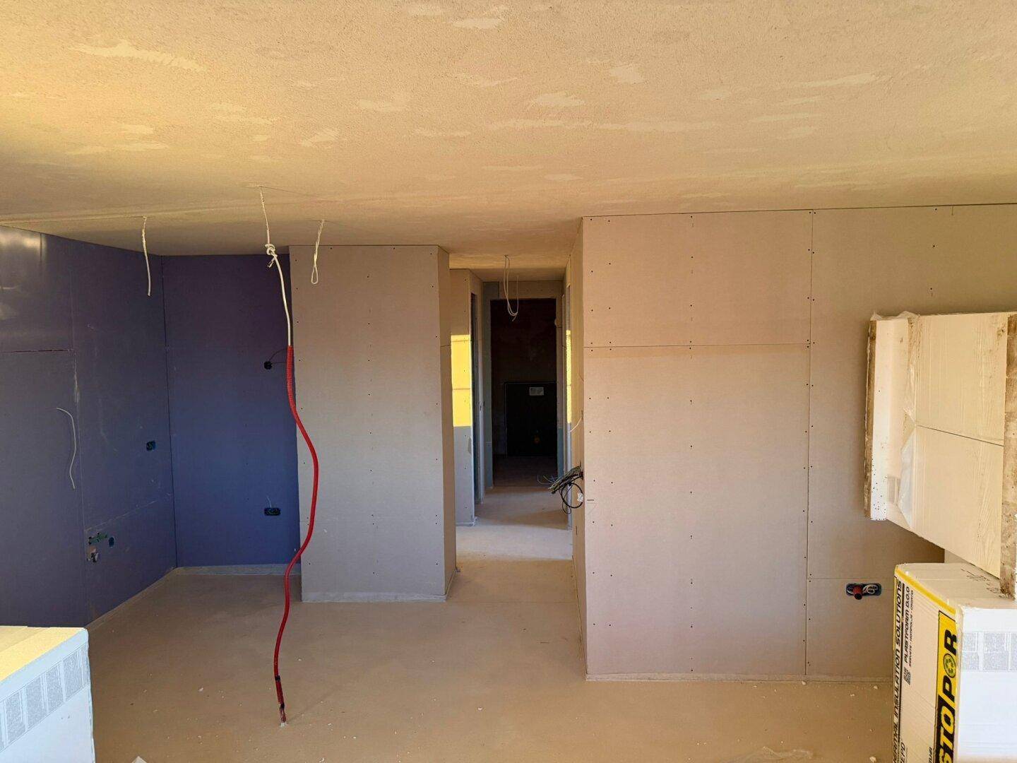 Innenraum im Rohbau mit Trockenbauwänden und sichtbaren Elektroinstallationen.