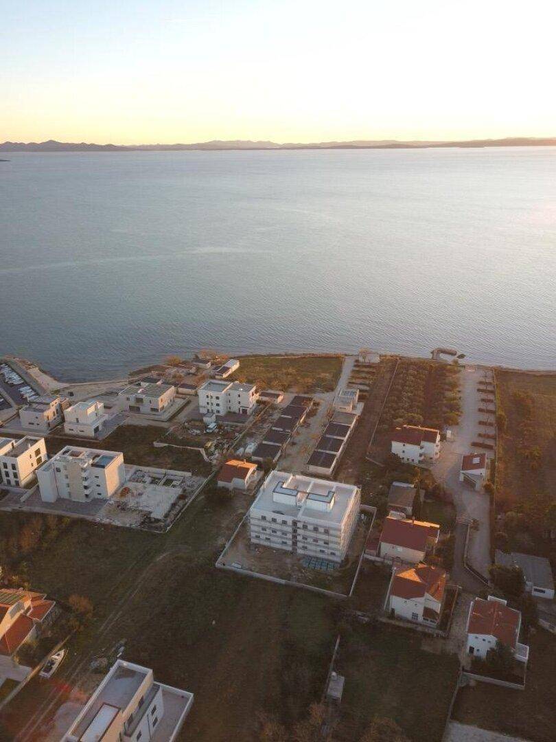 Luftaufnahme der im Bau befindlichen Wohnanlage direkt am Meer bei Sonnenuntergang mit weitem Blick.