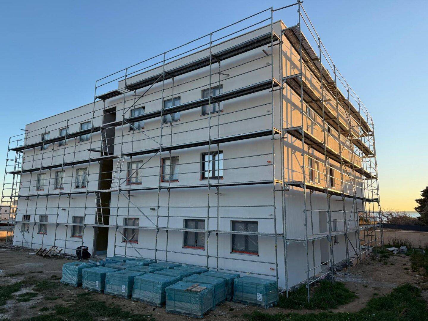 Neubau in der Bauphase, vollständig mit Gerüst umgeben, bereit für die Fassadenarbeiten.