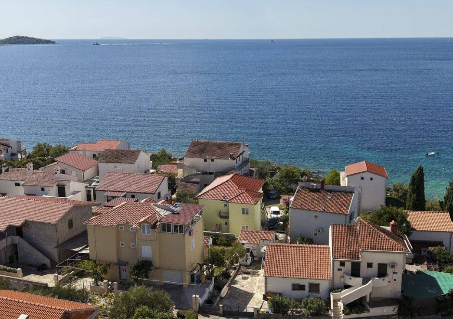 Weitläufiger Blick über die Dächer der Küstenhäuser zum tiefblauen Meer.