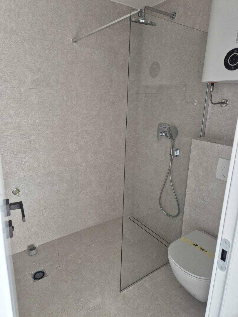 Modernes Badezimmer mit begehbarer Dusche, Wand-WC und hellen Fliesen.