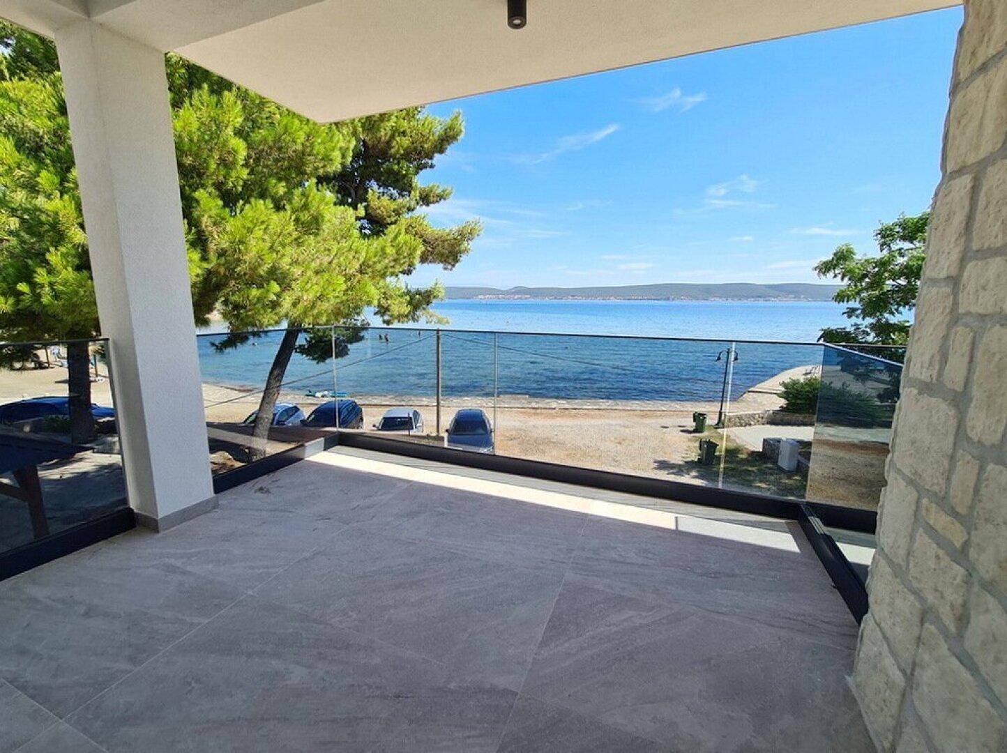 Geräumiger Balkon mit Glasgeländer und atemberaubendem Panoramablick auf das Meer und die Küste.