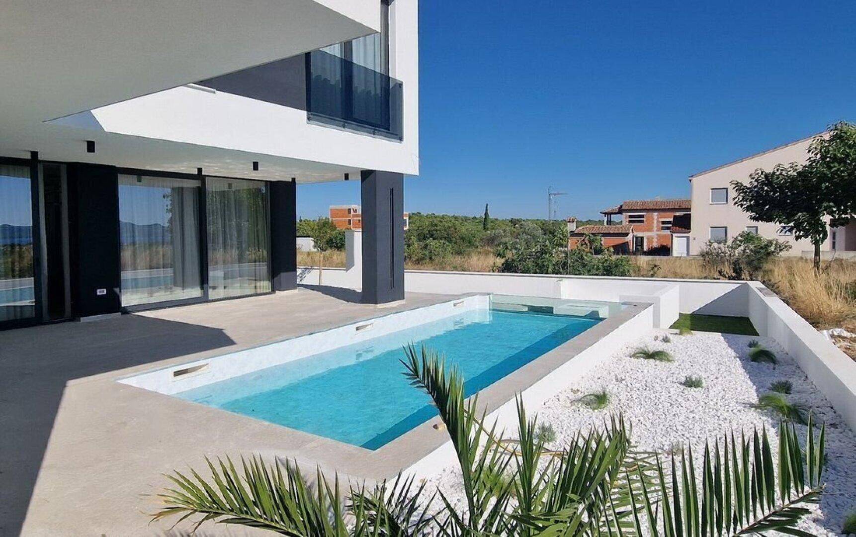 Seitlicher Blick auf die moderne Villa mit integriertem Pool und minimalistischer Gartengestaltung.