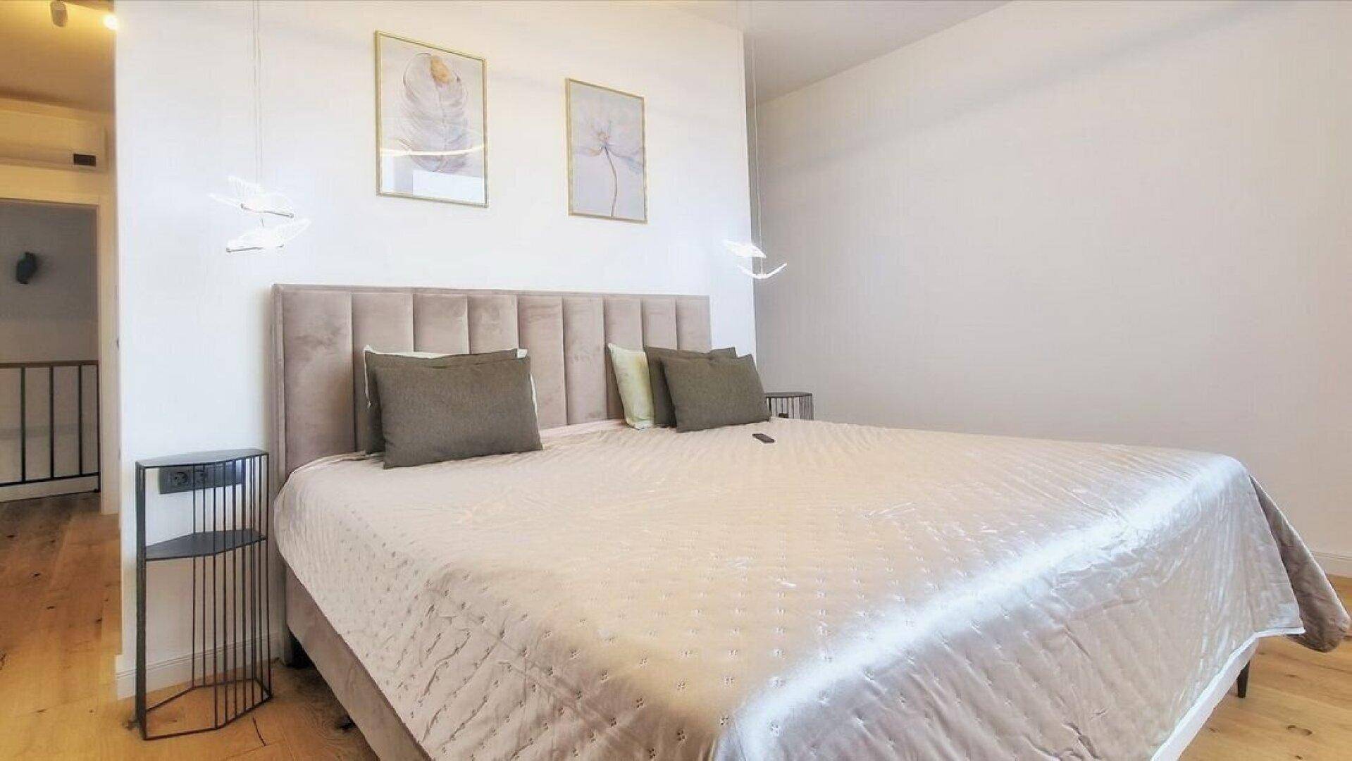 Gemütliches Schlafzimmer mit gepolstertem Kopfteil, weicher Bettwäsche und minimalistischer Dekoration.