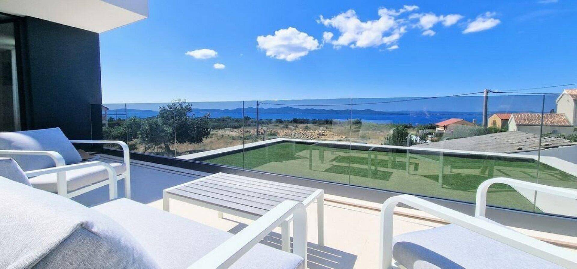 Geräumiger Balkon mit modernen Lounge-Möbeln und einem weiten Blick auf das Meer und die Küste.