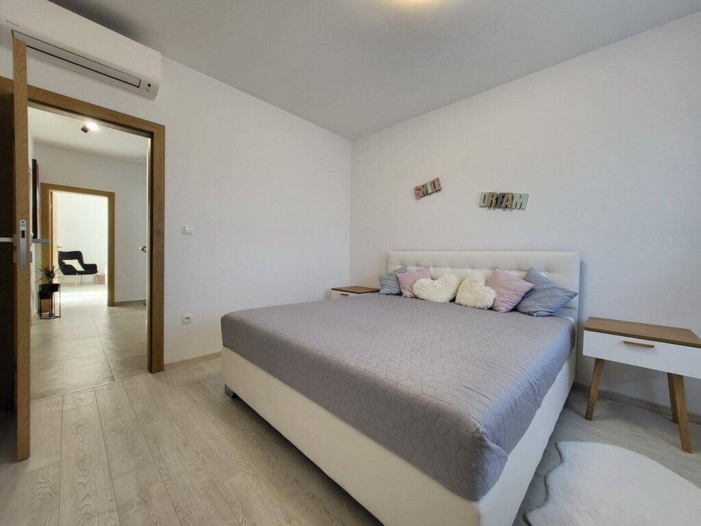 Gemütliches Schlafzimmer mit Doppelbett, hellen Kissen und Holzboden.
