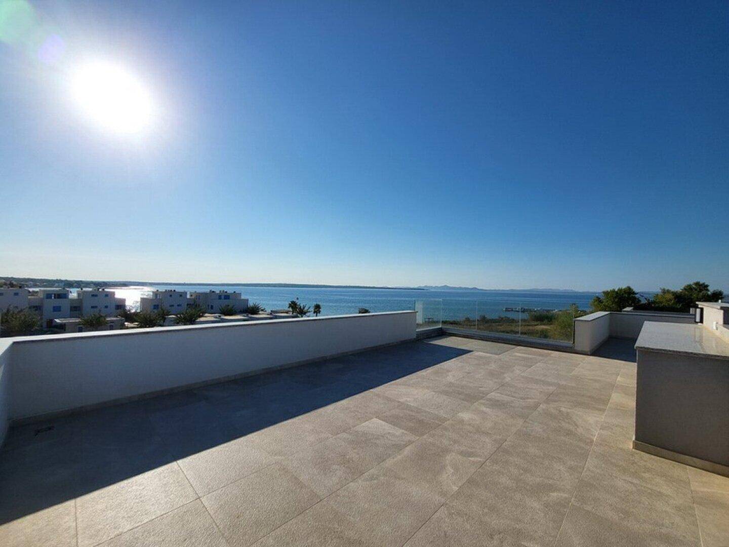 Weitläufige Dachterrasse mit atemberaubendem Meerblick unter strahlend blauem Himmel.