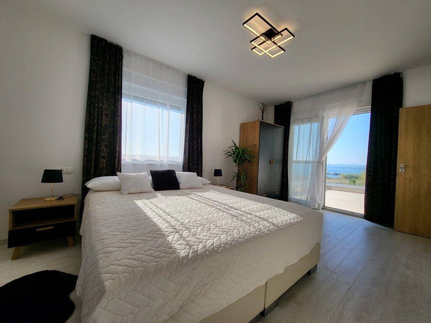 Helles Schlafzimmer mit Zugang zu einem Außenbereich und Blick auf das Meer.