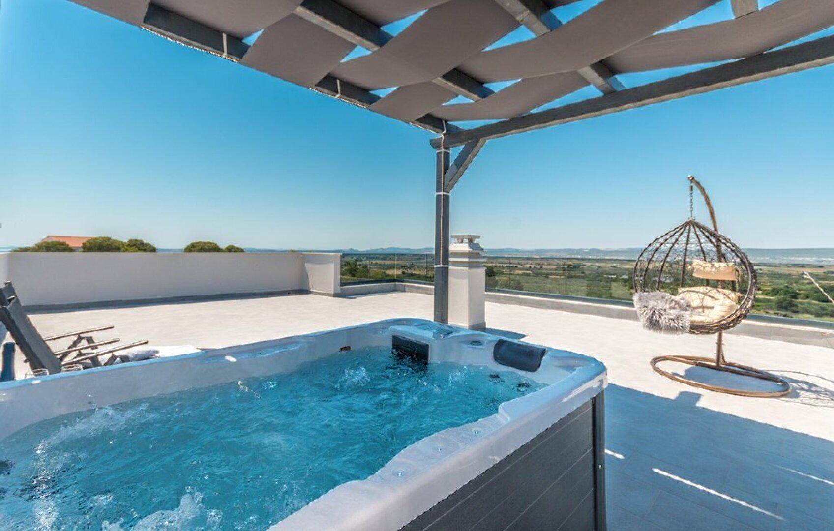 Entspannende Dachterrasse mit Whirlpool, Hängesessel und Panoramablick.