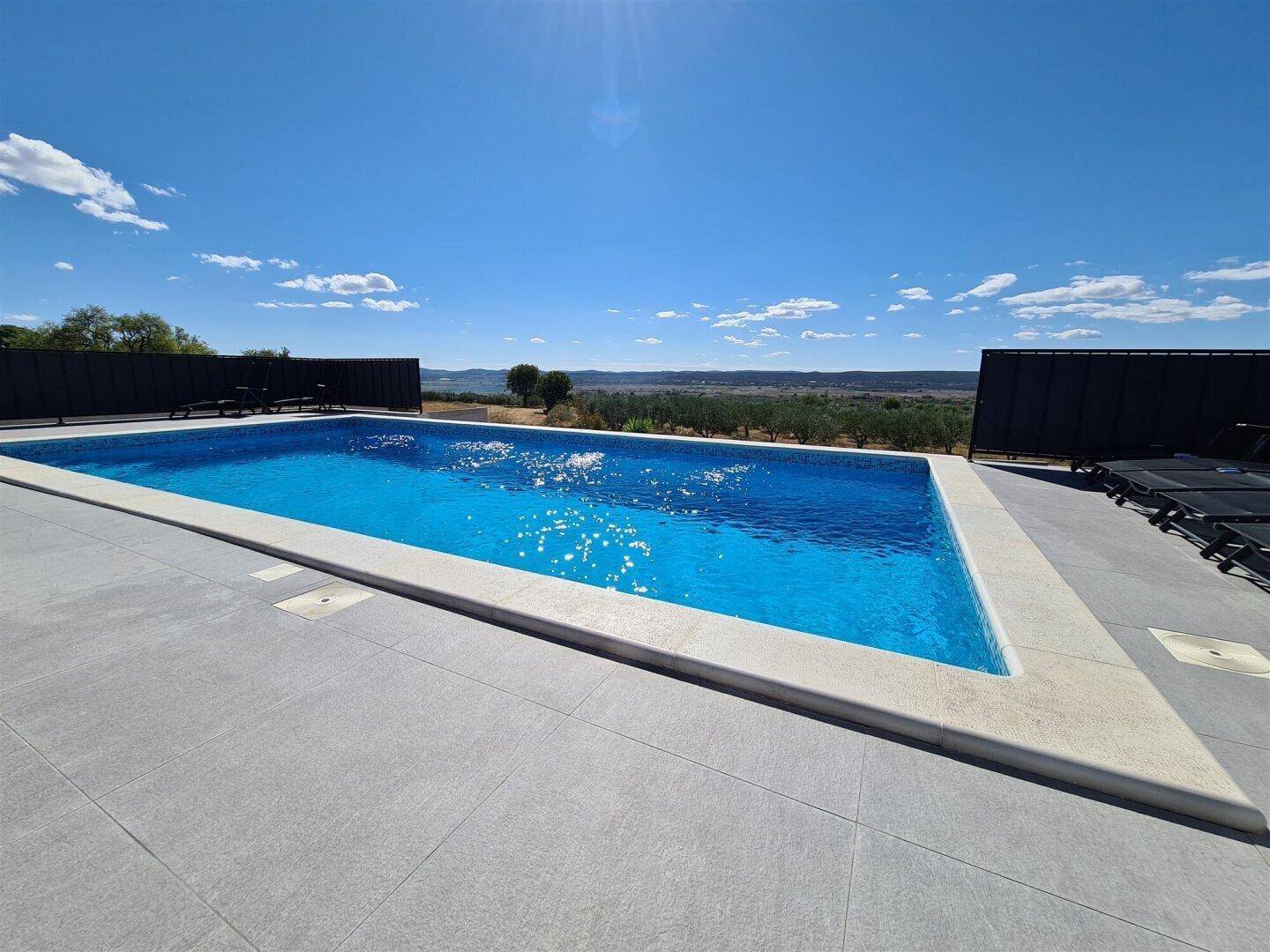 Großer Swimmingpool mit Liegeflächen und weitem Blick über die Landschaft.