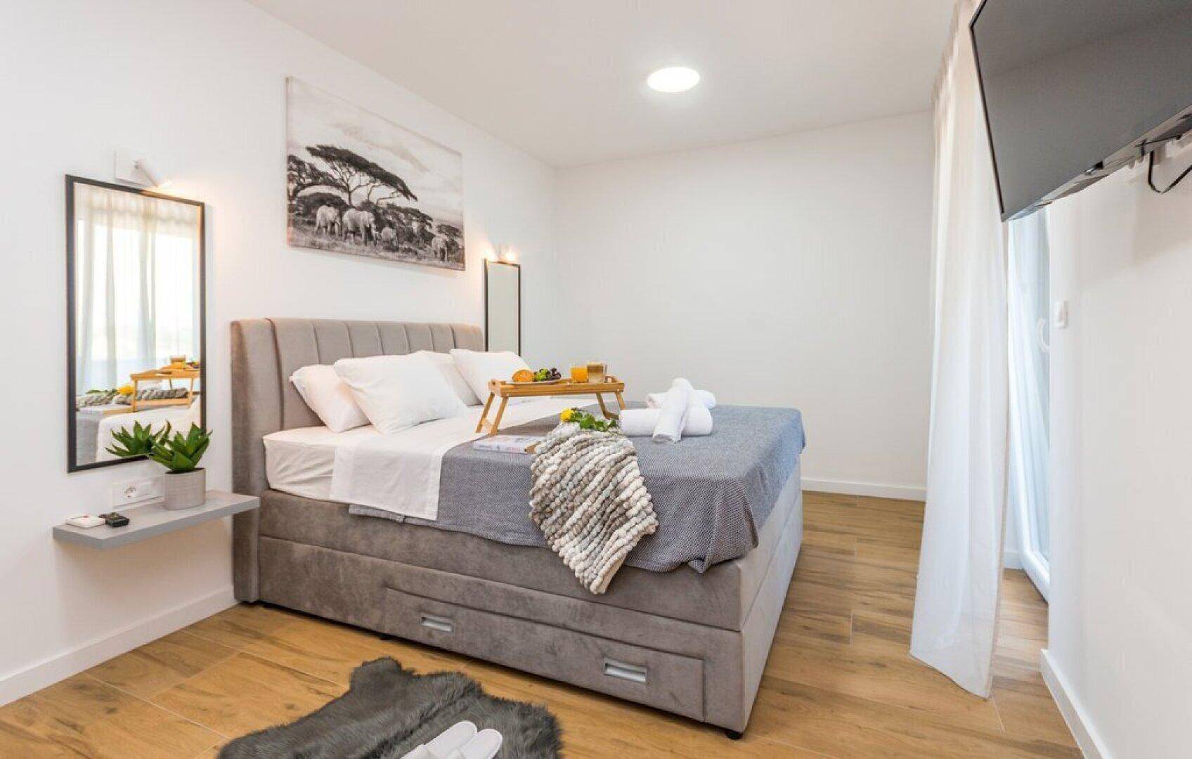 Gemütliches Schlafzimmer mit großem Bett, Holzboden und schlichter, moderner Einrichtung.
