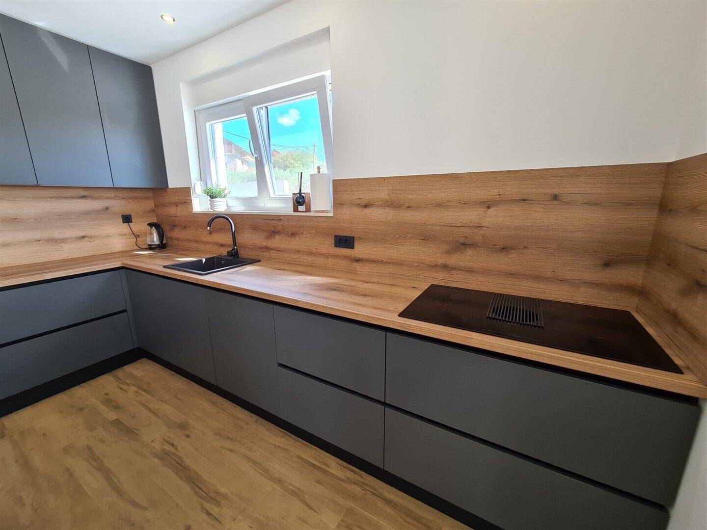 Moderne Einbauküche mit Induktionskochfeld, Holz-Arbeitsplatten und viel Stauraum.