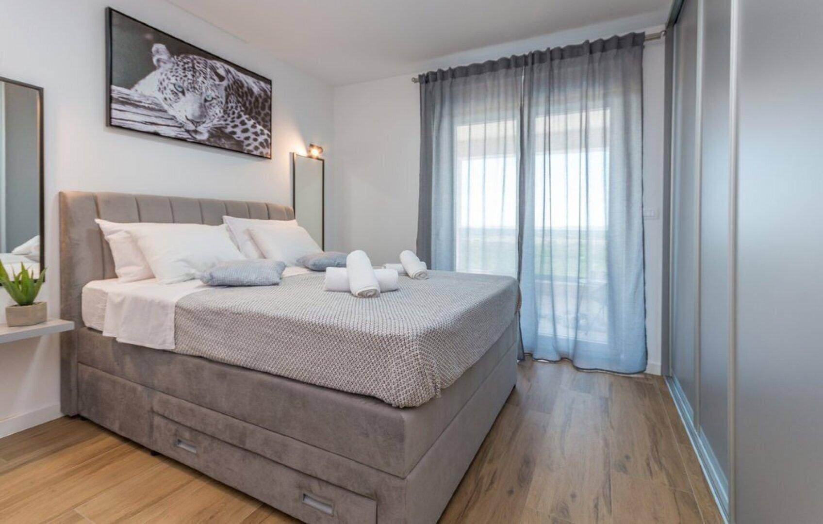 Helles Schlafzimmer mit Doppelbett, Einbauschränken und Blick ins Grüne.