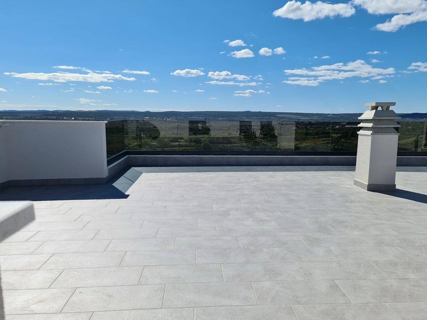 Geräumige Dachterrasse mit Fliesenboden und Panoramablick über die Landschaft.