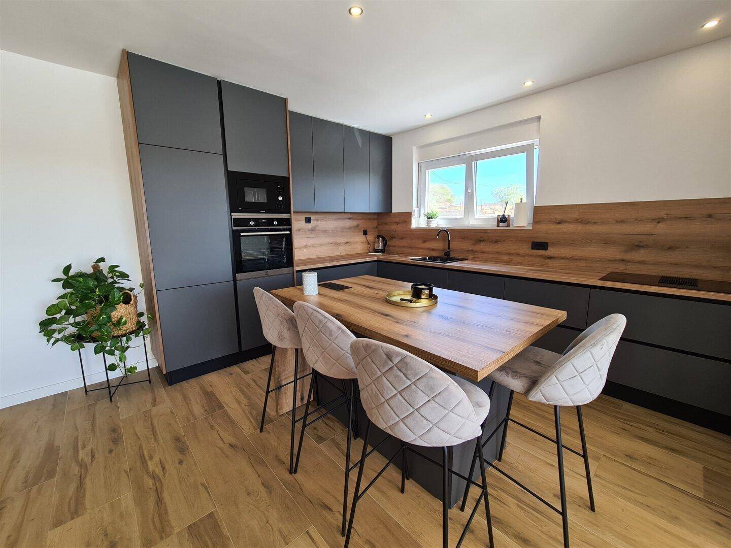 Moderne Küche mit dunklen Schränken, Holzdetails und einer Kücheninsel mit Sitzgelegenheiten.