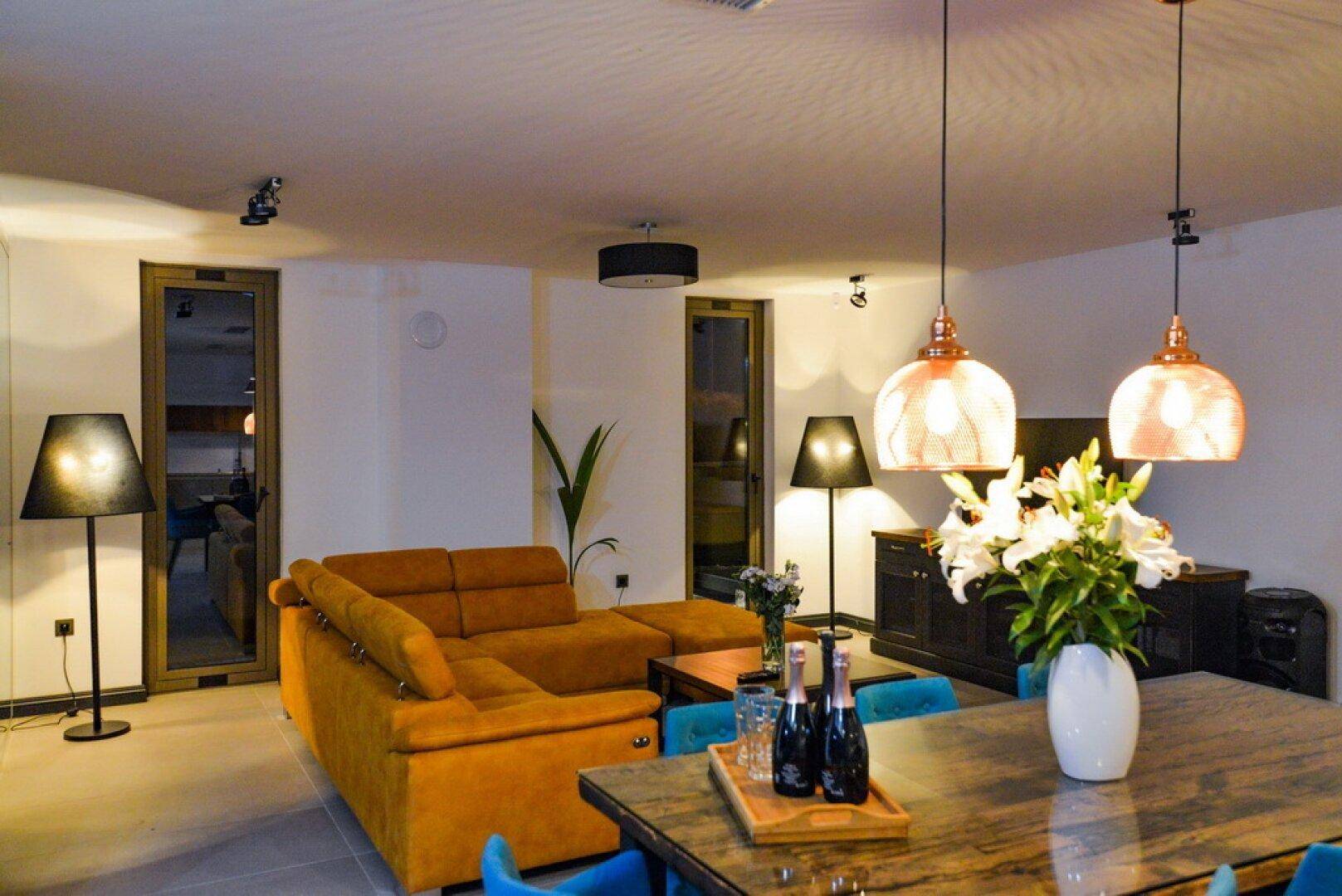 Gemütlicher Wohnbereich mit orangefarbenem Sofa und Essbereich mit blauen Stühlen.