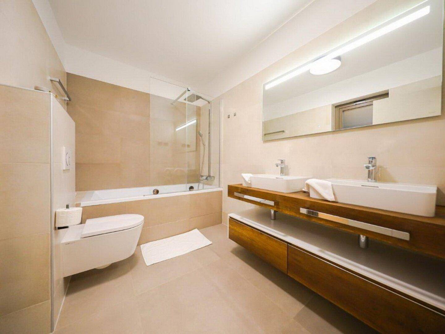 Geräumiges Badezimmer mit Doppelwaschbecken, Badewanne und großem Spiegel.