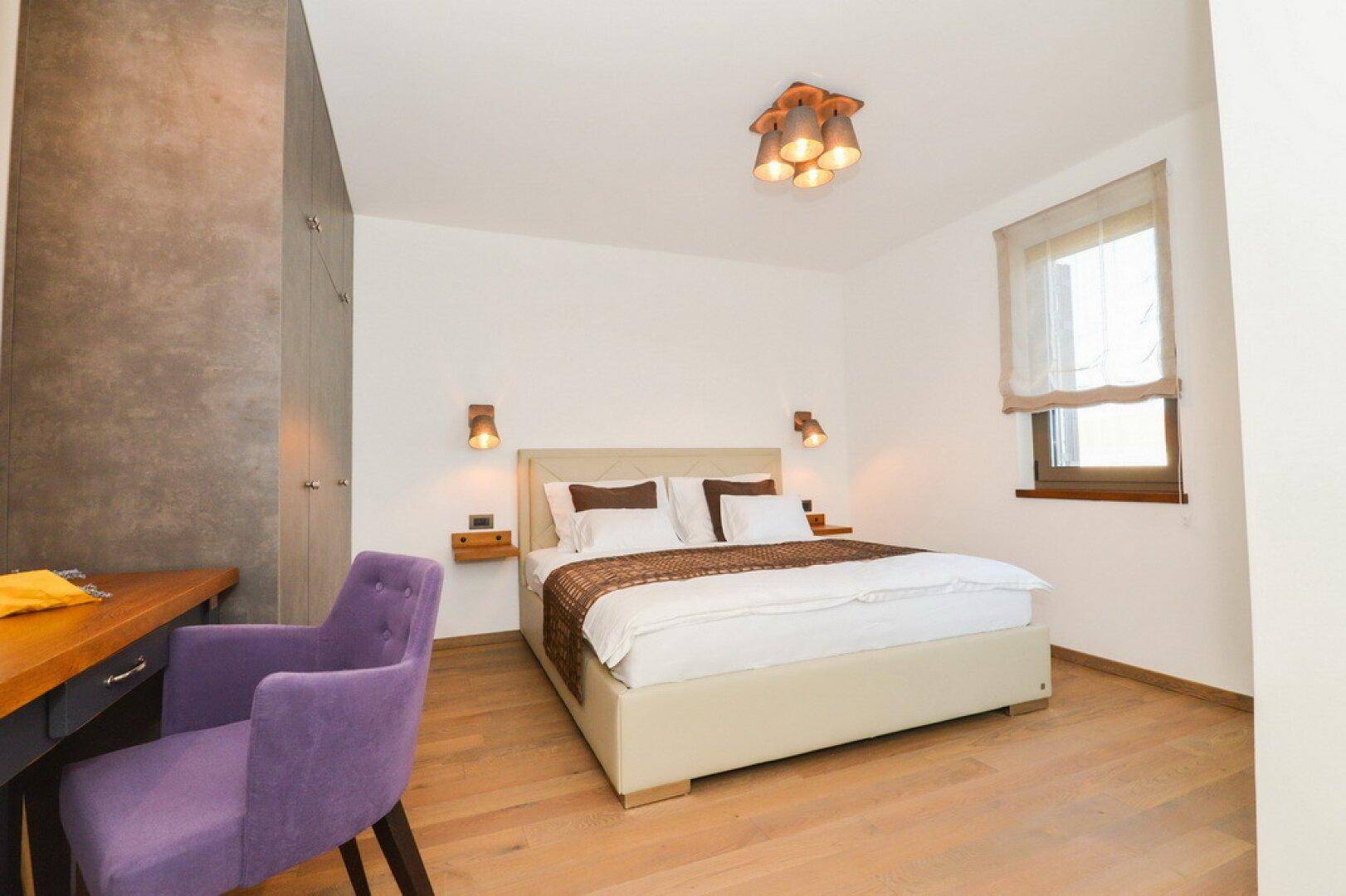 Helles Schlafzimmer mit Doppelbett, Holzboden und Einbauschränken.