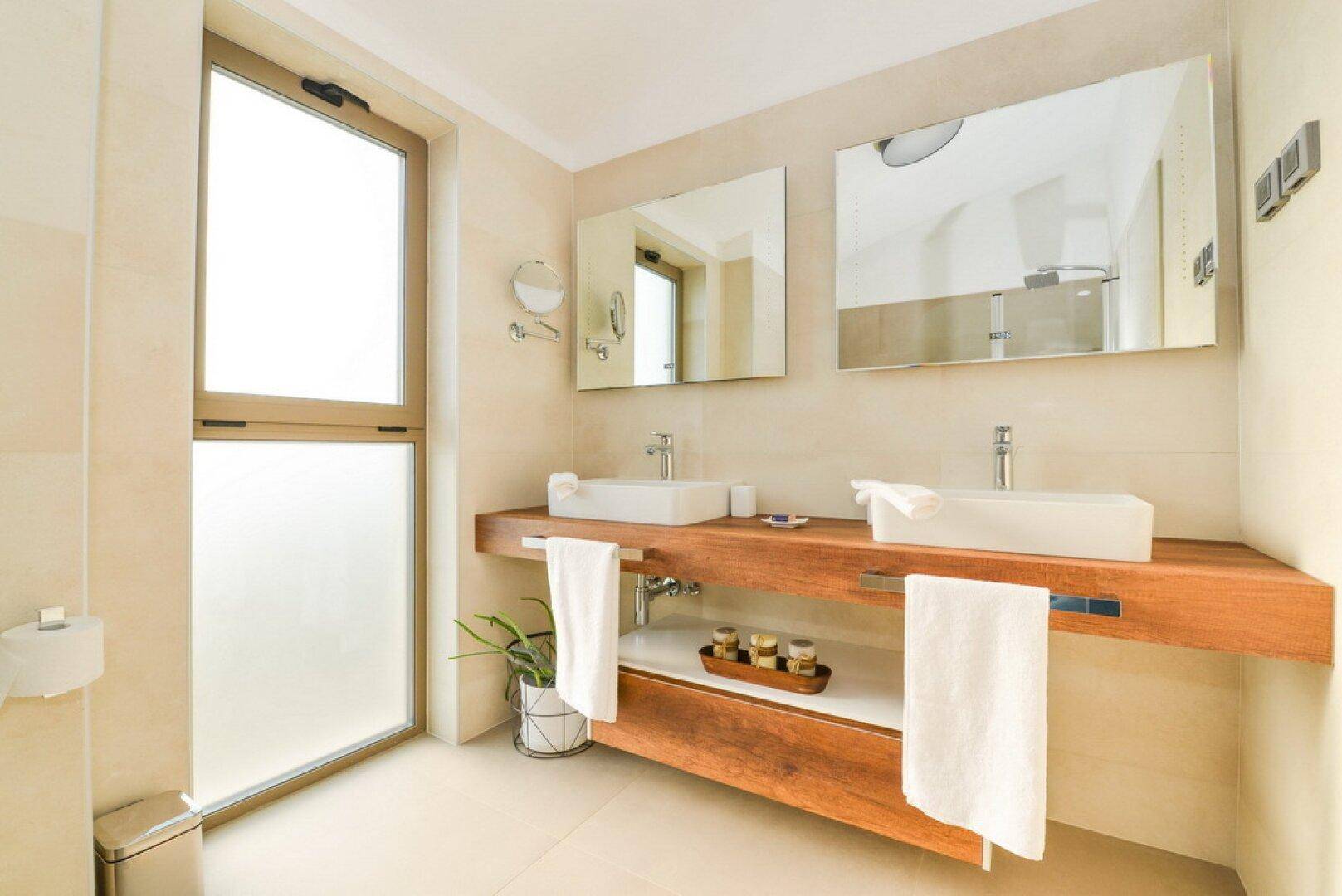 Modernes Badezimmer mit Doppelwaschbecken, Holzunterschrank und großem Fenster.