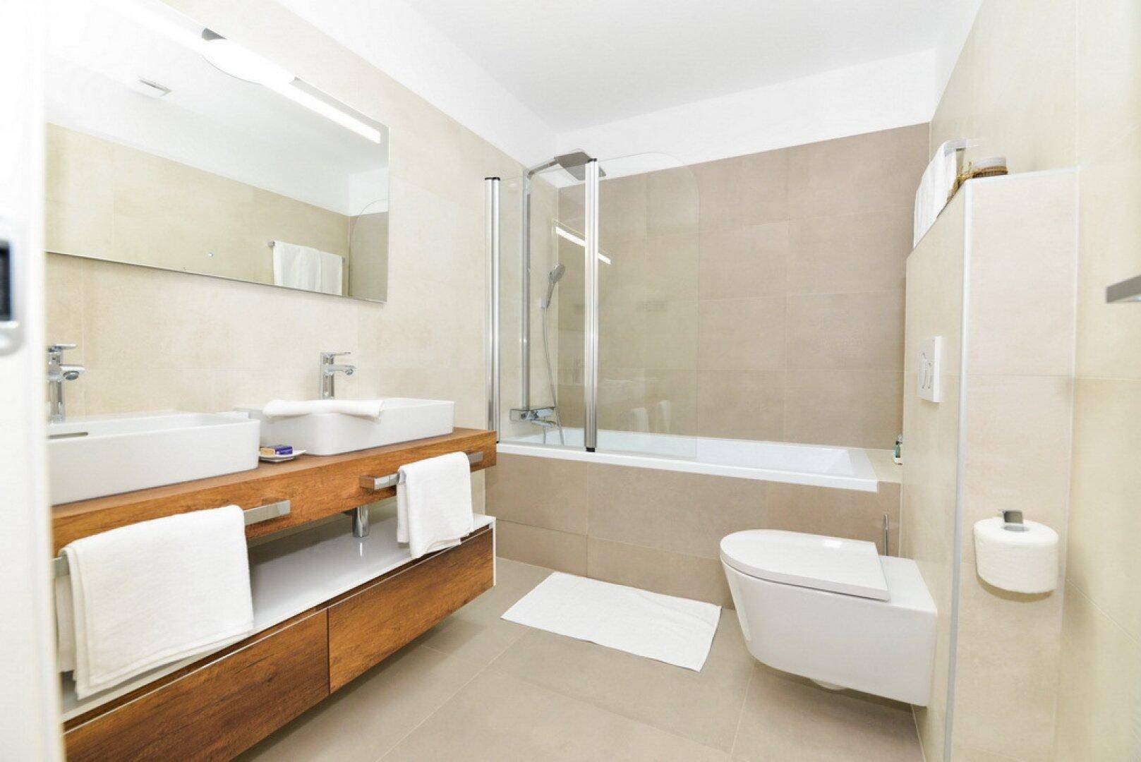 Elegantes Badezimmer mit Badewanne, Duschabtrennung und wandhängendem WC.