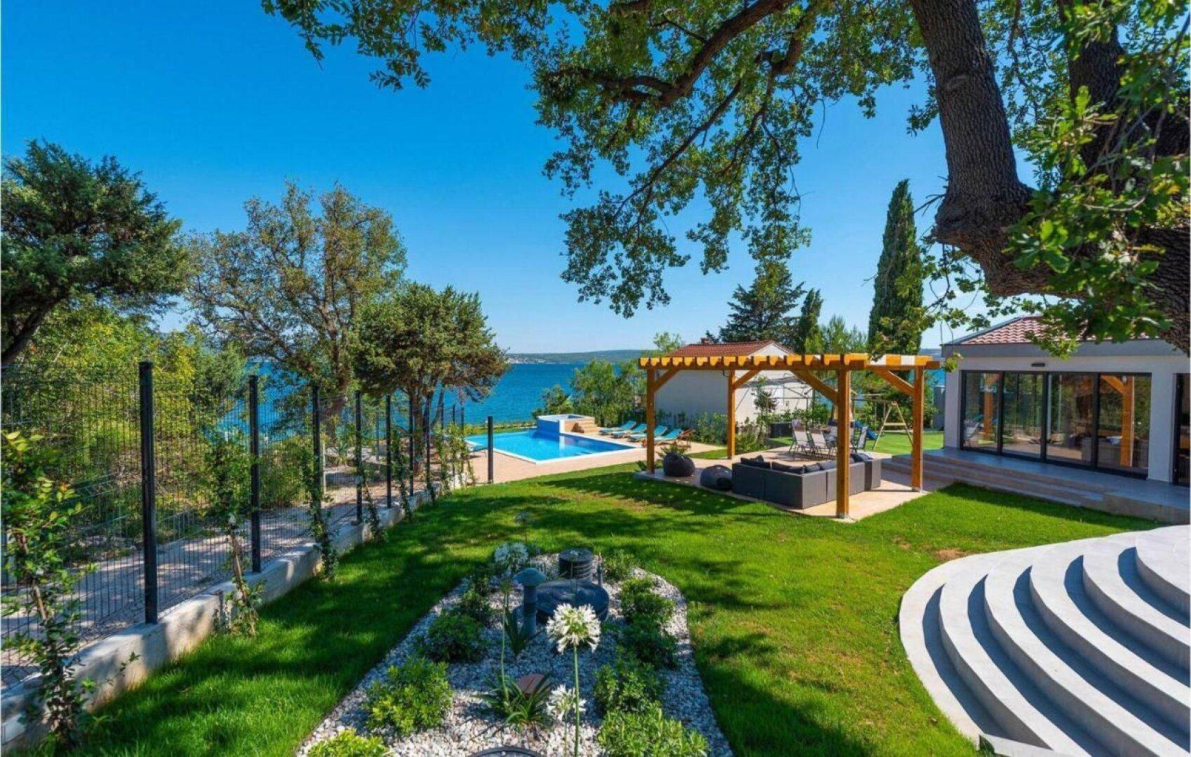 Gepflegter Gartenbereich mit Pool, Pergola und Meerblick, ideal zum Entspannen.