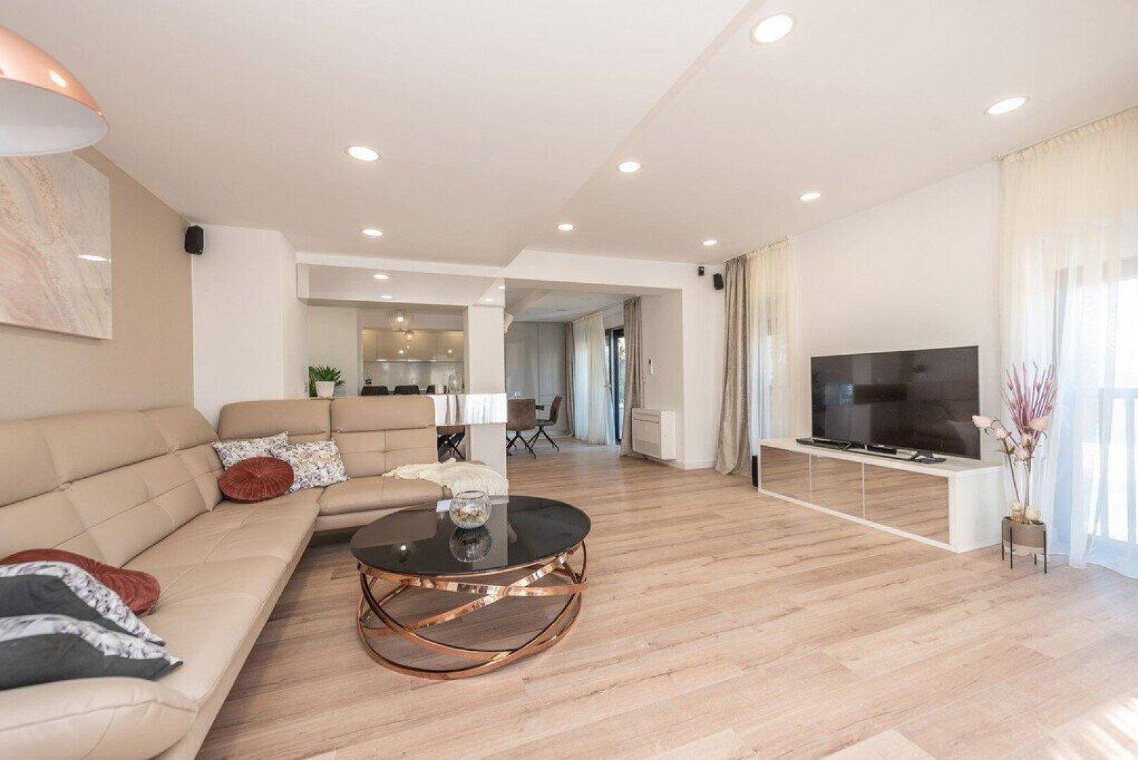 Helles Wohnzimmer mit beigem Sofa, modernem Couchtisch und Holzboden.