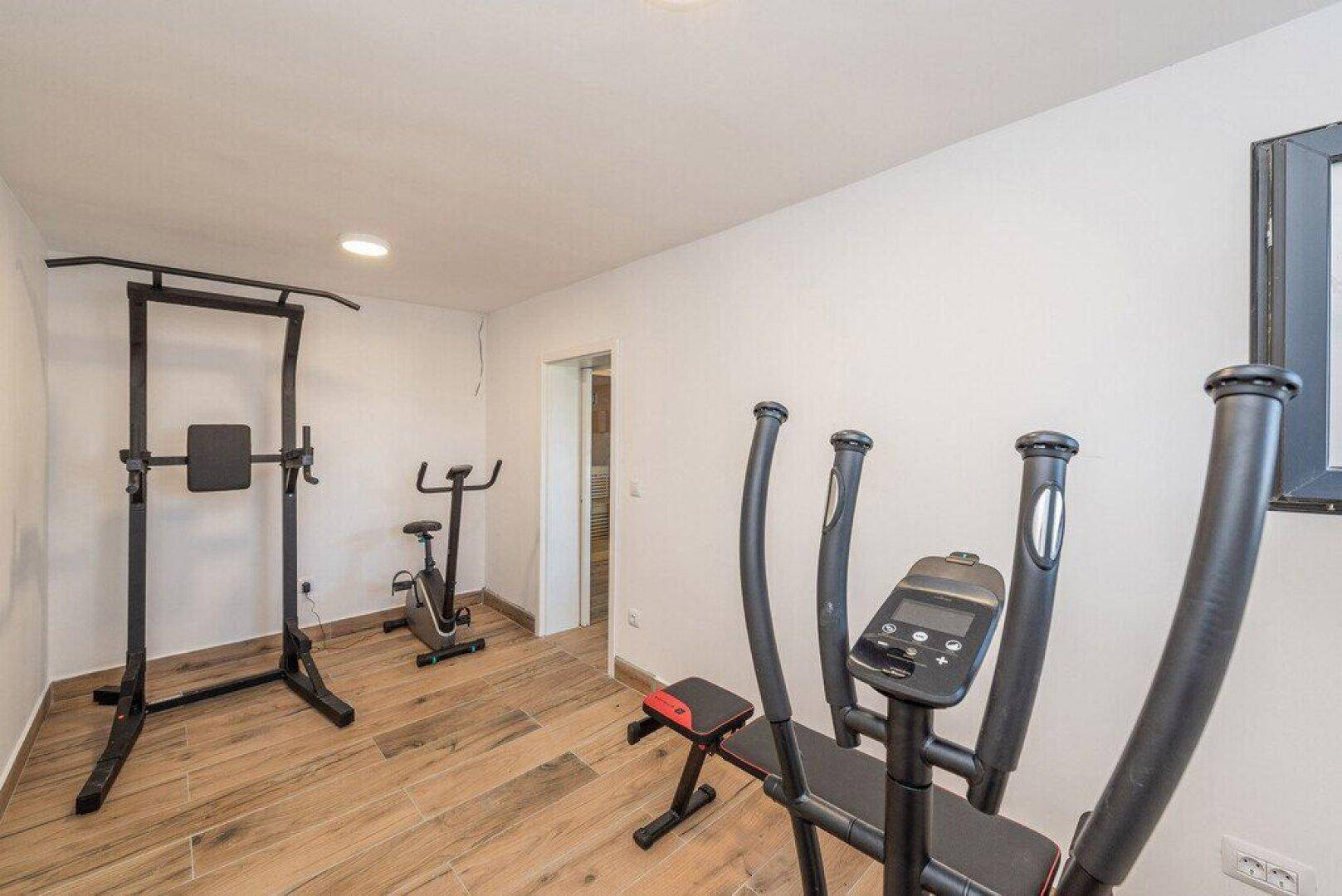 Kleiner Fitnessraum mit verschiedenen Trainingsgeräten für das tägliche Workout.