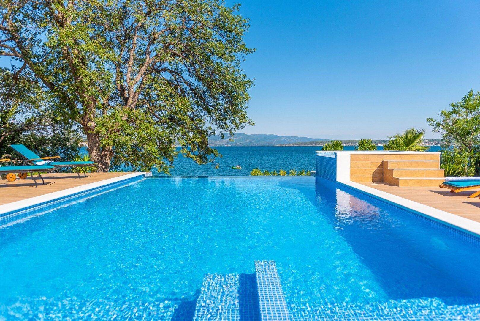Großer Infinity-Pool mit atemberaubendem Meerblick und Holzdeck.