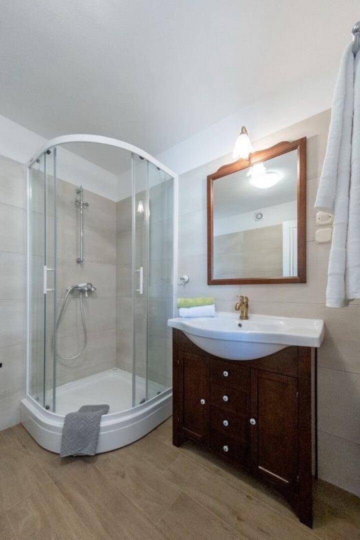 Modernes Badezimmer mit Duschkabine, Holzwaschtisch und Spiegel.