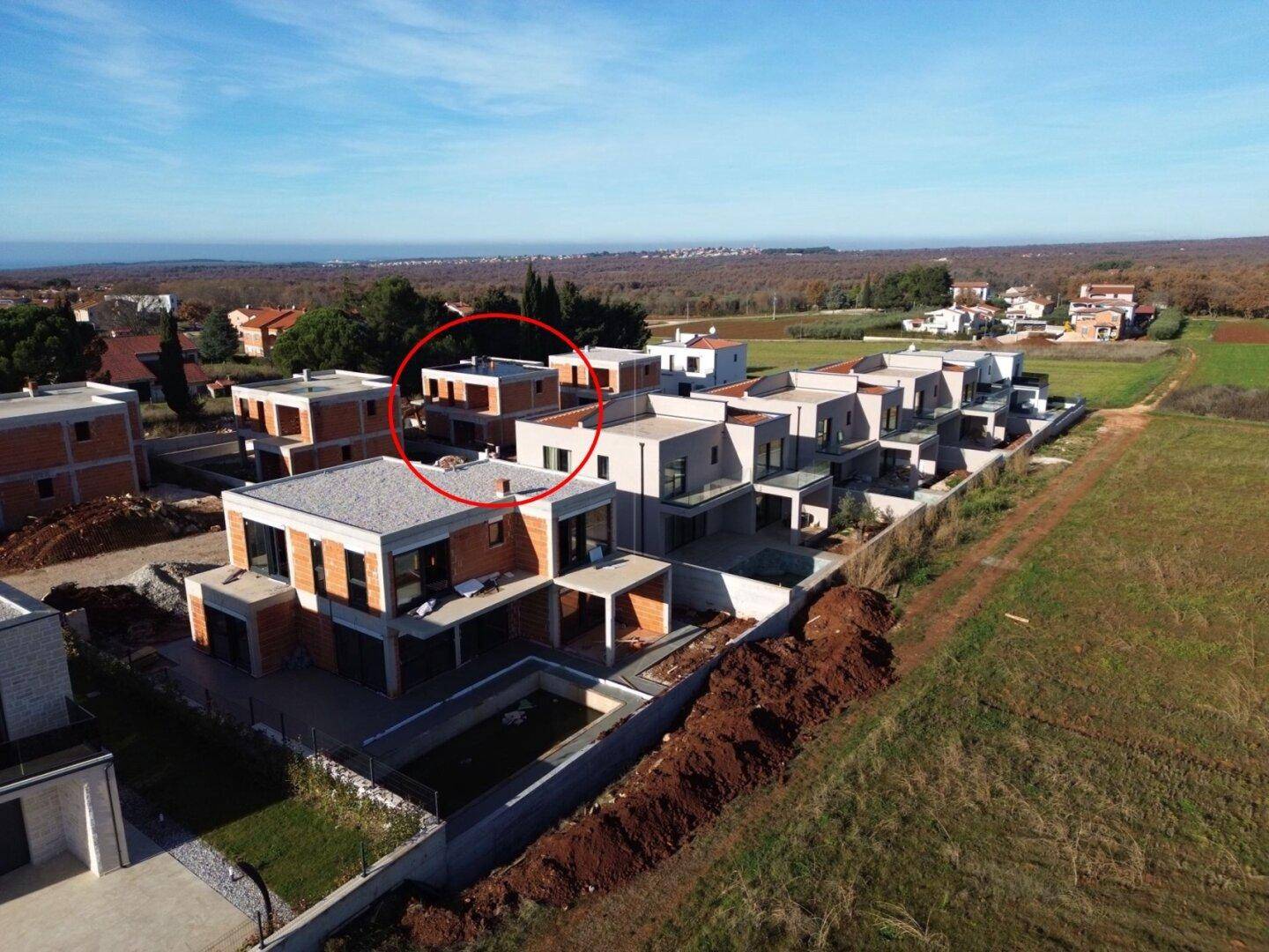 Luftaufnahme einer modernen Wohnsiedlung mit Neubauten und im Bau befindlichen Häusern in ländlicher Umgebung.