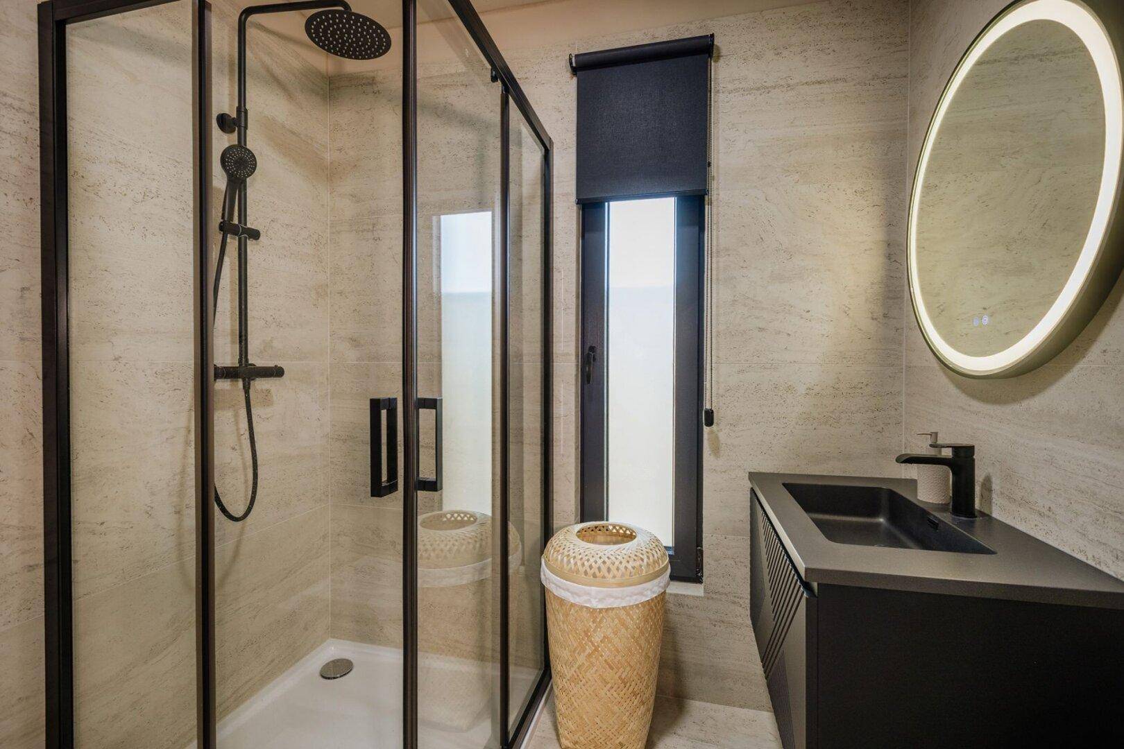 Modernes Badezimmer mit begehbarer Dusche, schwarzer Armatur und beleuchtetem Spiegel.
