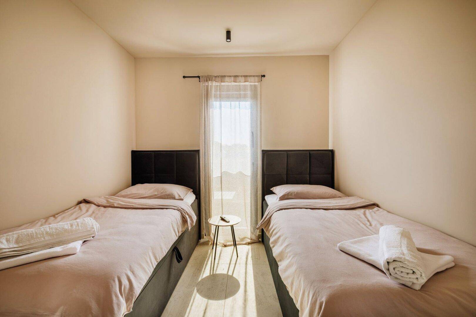 Gemütliches Schlafzimmer mit zwei Einzelbetten und hellem Tageslicht.