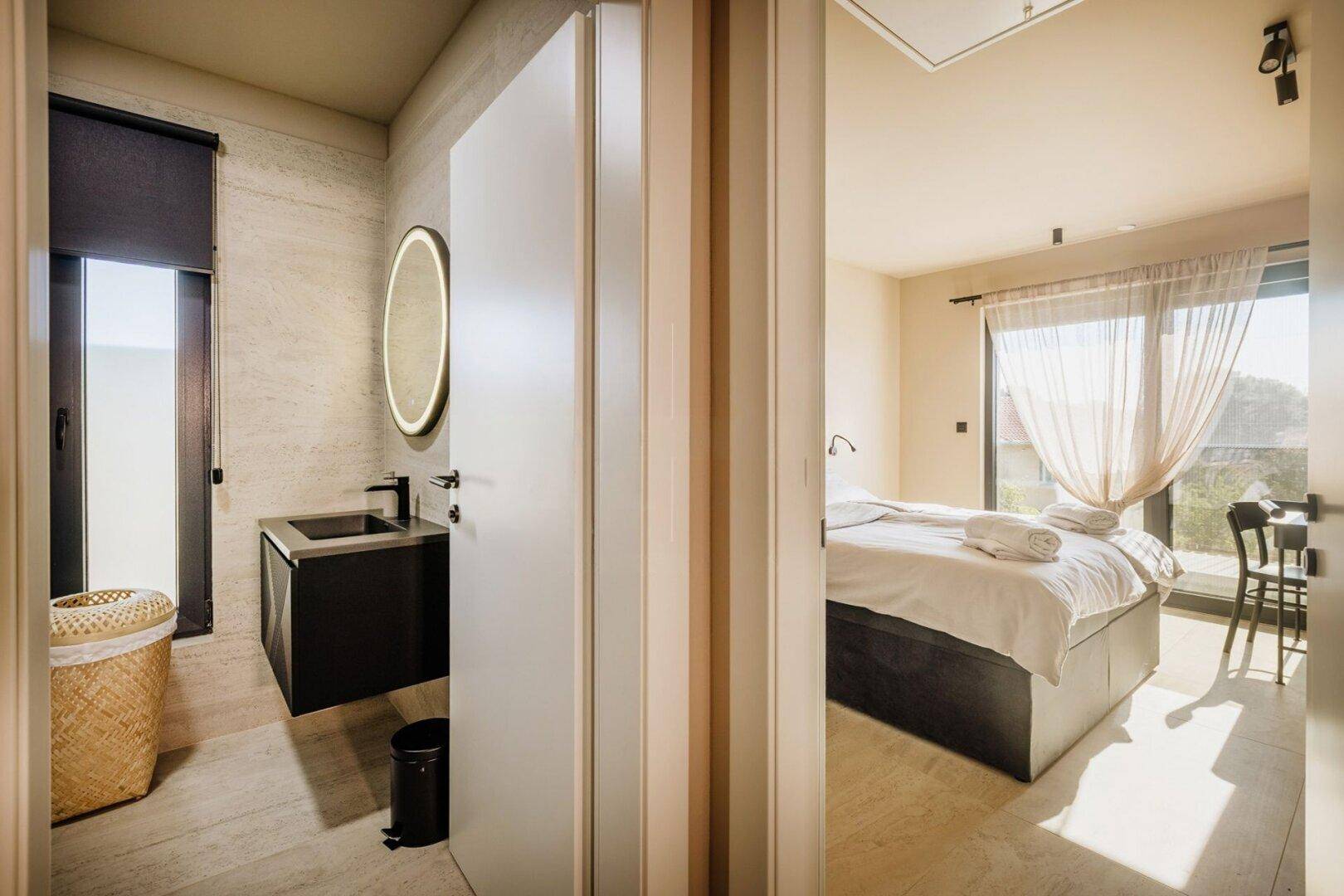 Schlafzimmer mit Zugang zu einem modernen Badezimmer und viel Tageslicht.