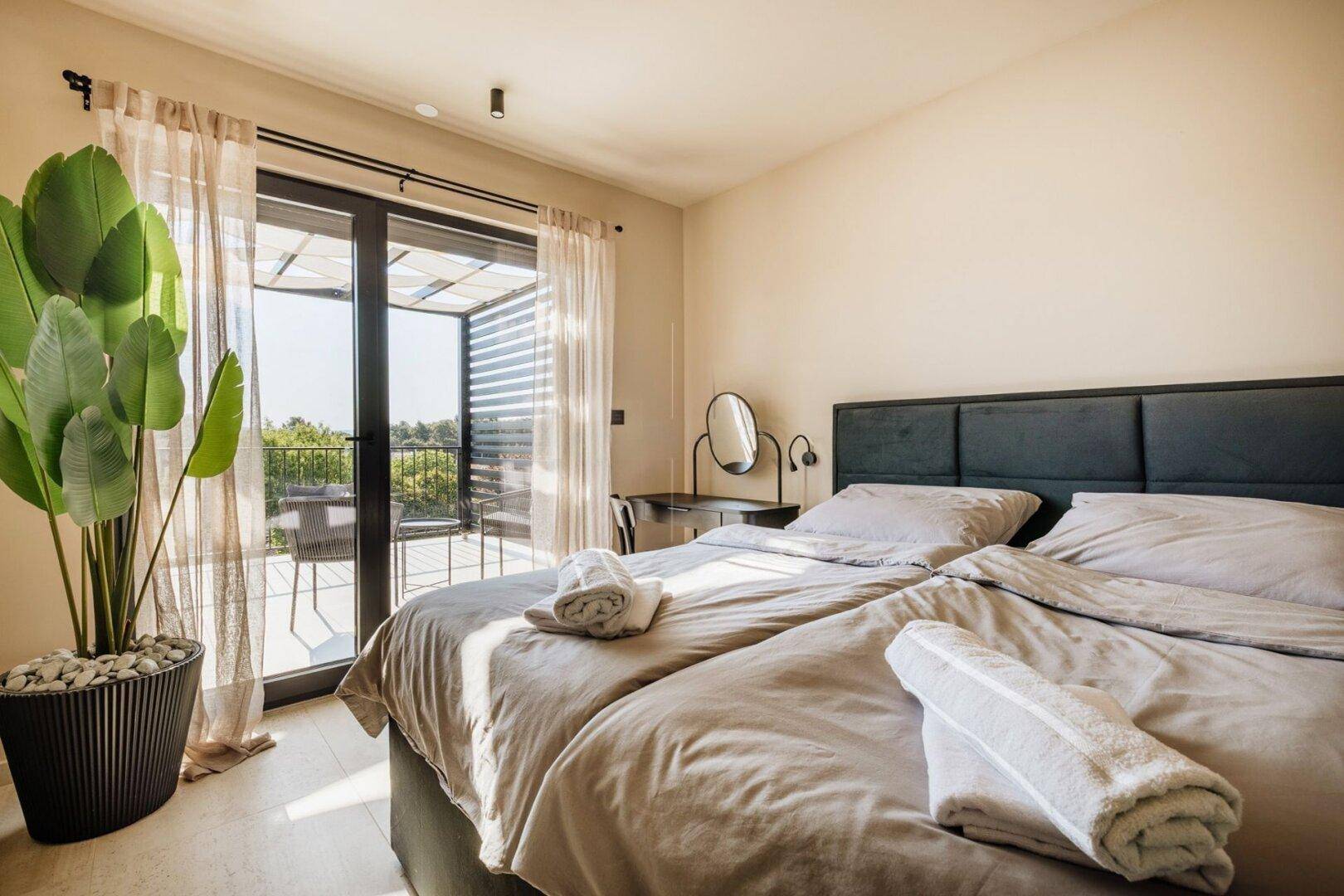 Helles Schlafzimmer mit zwei Einzelbetten, Balkonzugang und Blick ins Grüne.